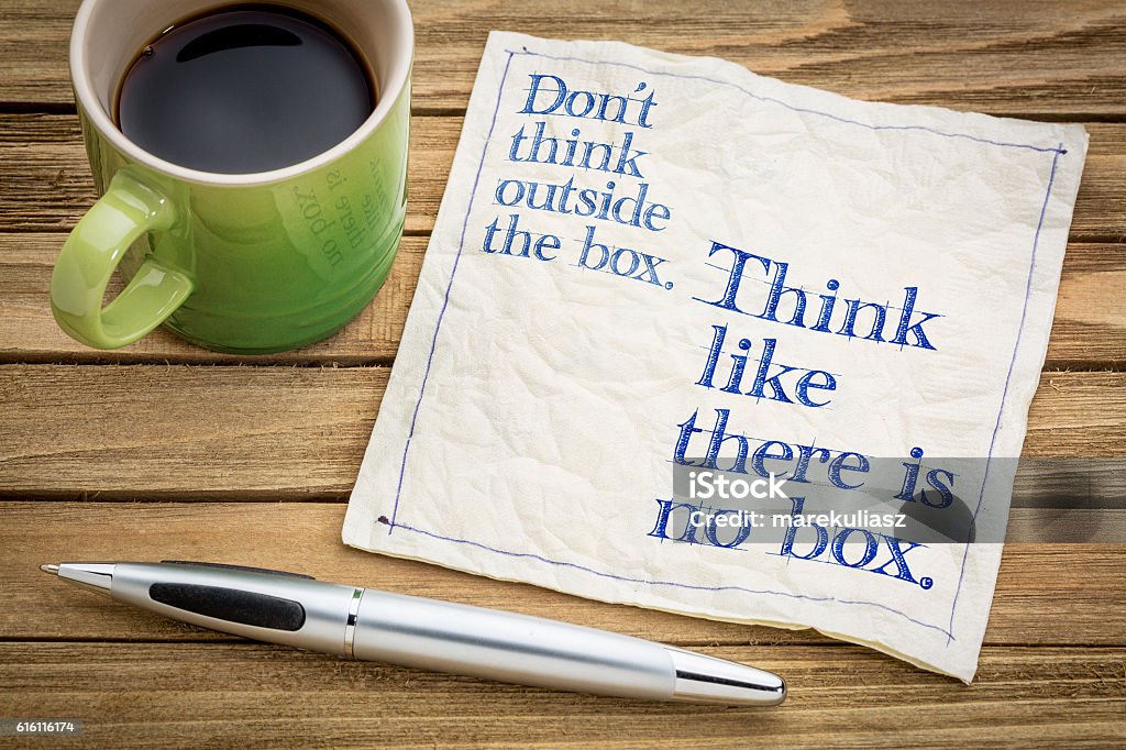 Think like there is no box. Don't think outside the box. Think like there is no box.- handwriting on a napkin with a cup of espresso coffee Thinking Outside The Box Stock Photo