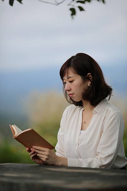istock GIrl reading book at outdoor cafe 616128882