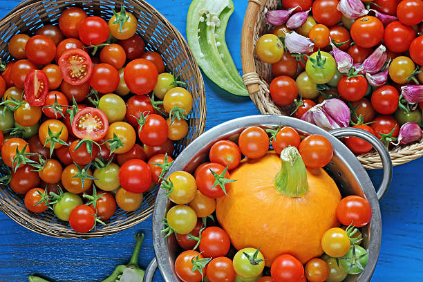 Red and yellow cherry tomatoes, pepper, pumpkin and garlic on a blue background, the top view. Vegetable background.