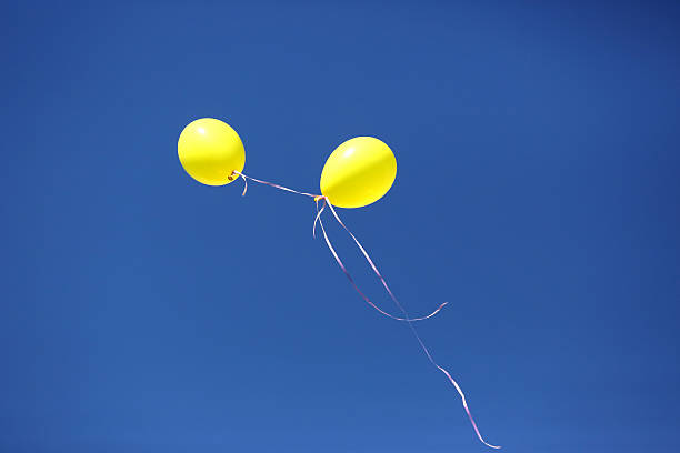 istock two yellow balloon against a blue sky 616130868