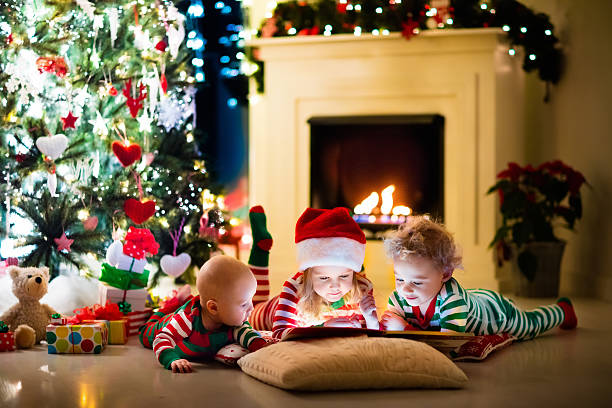 istock Children in pajamas reading book under Christmas tree 616131058