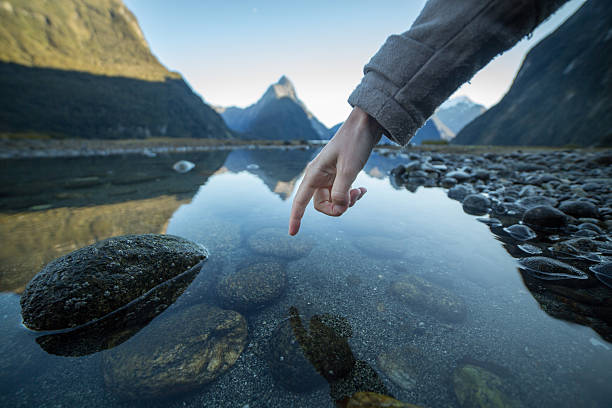 istock Finger touches surface of mountain lake 616132514
