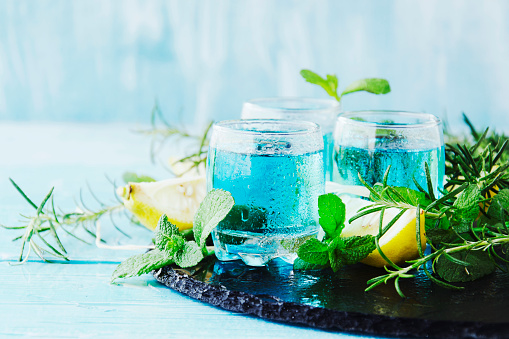 Blue curacao liqueur or sambuca with lemon on the wooden table, selective focus