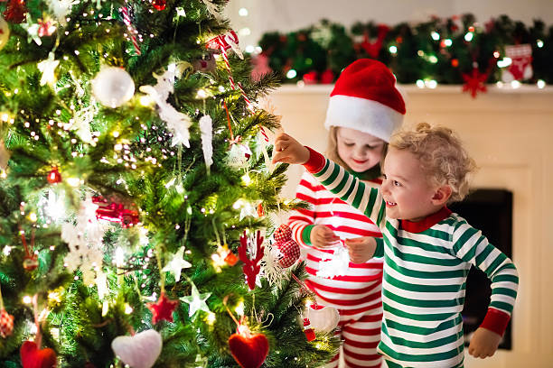 istock Kids in red and green striped pajamas under Christmas tree 616219384