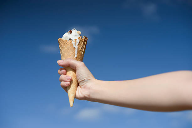 istock woman hand holding ice cream cone on a hot summer 616222144