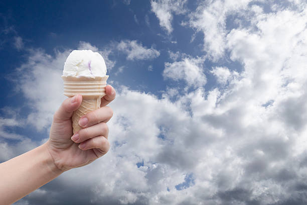 istock woman hand holding Ice cream with summer blue sky 616222284