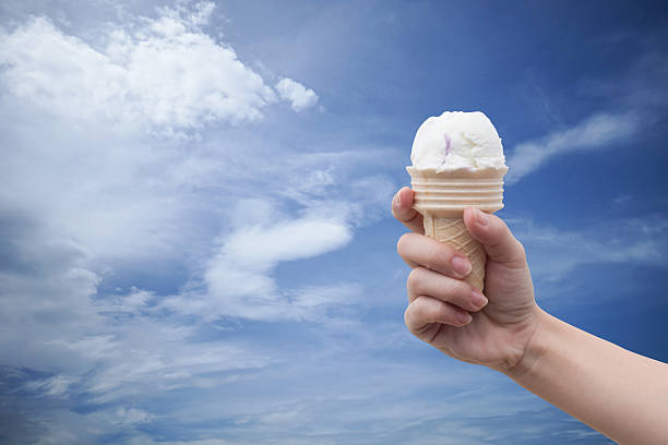 istock woman hand holding Ice cream with summer blue sky 616222298