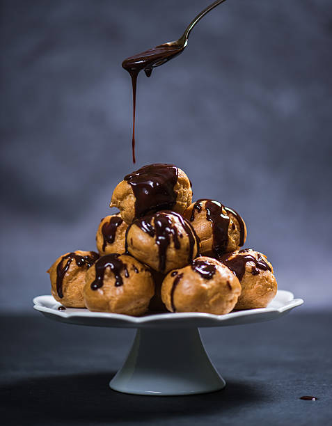 топпинг profiterole башня с шоколадом - профитроль стоковые фото и �изображения