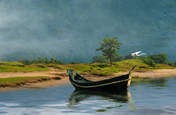 old fishing boat docked in a lake infront of a beautiful make in bangladesh