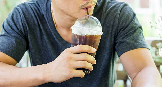 istock Man drinking an iced coffee in a coffee shop. 616225850