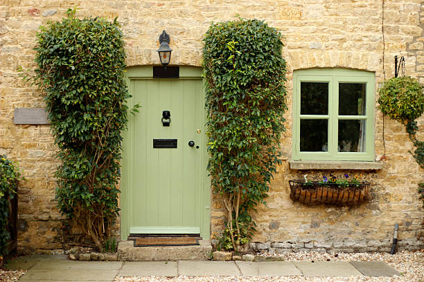 front of cottage with green door and window - huisje stockfoto's en -beelden