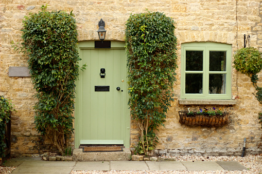 A front of a cottage with a green door and window.