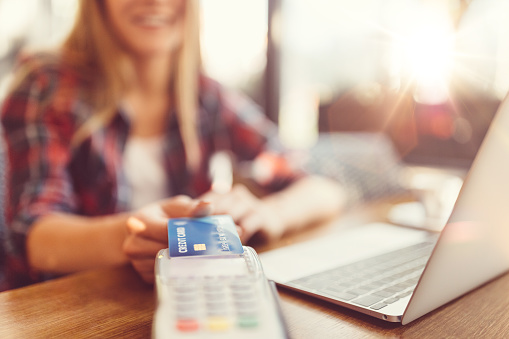 Woman touching credit card on the credit card reader for contactless payment  +++++ Note for the inspector: Credit card is fake +++++