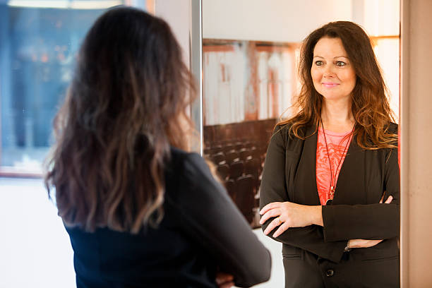 brunette woman looking at herself in mirror beautiful brunette woman looking at herself in mirror looking in mirror stock pictures, royalty-free photos & images