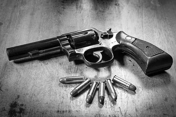 Photo of Old hand gun and bullets on wooden background