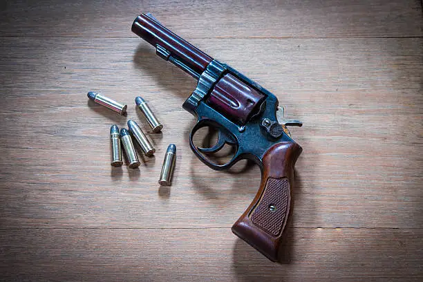 Photo of Old hand gun and bullets on wooden background