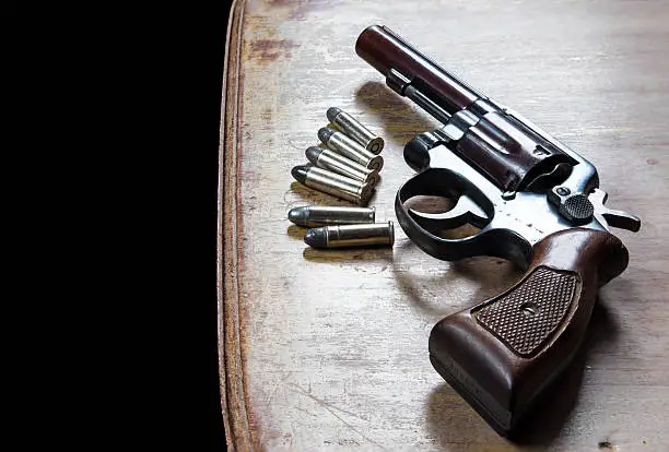 Photo of Old hand gun and bullets on wooden background