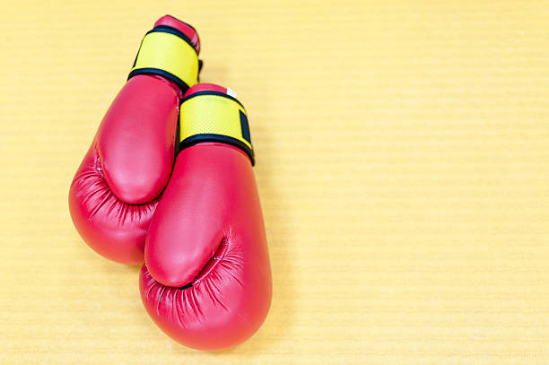istock Red boxing gloves lying on yellow mat 616244554