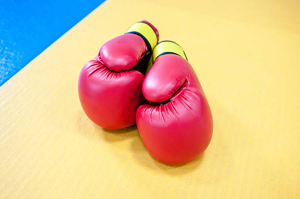 istock Red boxing gloves lying on yellow blue mat 616244608