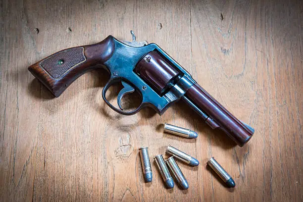 Photo of Old hand gun and bullets on wooden background