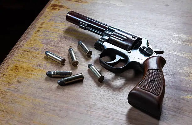 Photo of Old hand gun and bullets on wooden background