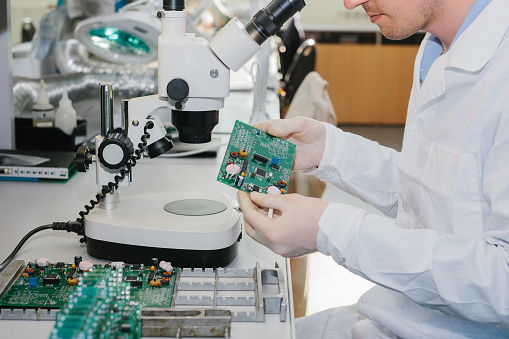 Microchip production factory. Technological process. Assembling the board. Chip. Professional. Technician. Computer expert. Manufacturing. Engineering.