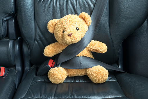 Teddy bear fijado en el asiento de atrás de un coche photo