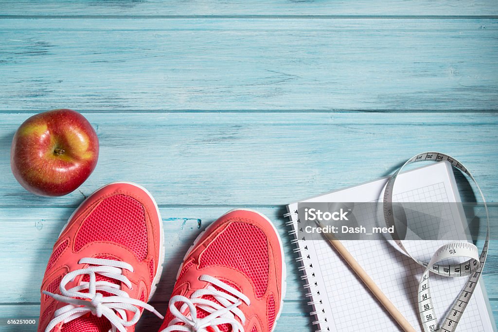 Concepto fitness, zapatillas rosas, manzana y cuaderno y cinta métrica - Foto de stock de Cuaderno de apuntes libre de derechos