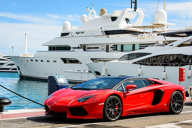 Luxury sports car and yachts at Puerto Banus in Marbella Marbella, Spain - October 13, 2016: Front view of a red super sport car (Lamborghini) parked alongside luxury yachts moored in the marina of Puerto Jose Banus on the Costa del Sol in Marbella, Spain. luxury craft stock pictures, royalty-free photos & images