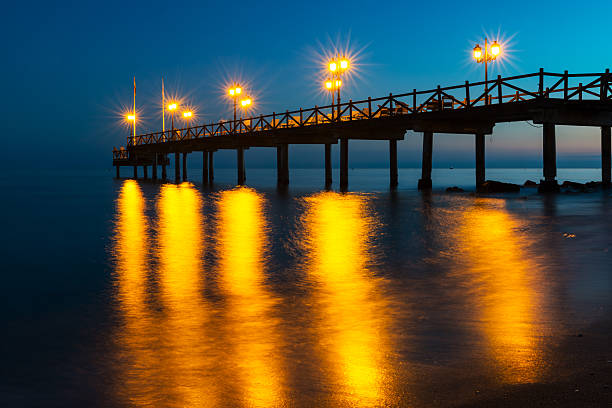 Illuminated wooden jetty on a beach in Marbella during sunset. Long exposure.