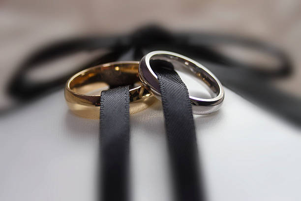 dos anillos de boda masculinos y femeninos unidos por cinta - men groom wedding red fotografías e imágenes de stock