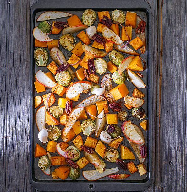verduras y frutas cortadas tostadas en una hoja de hornear. - raw potato sweet potato vegetable food fotografías e imágenes de stock
