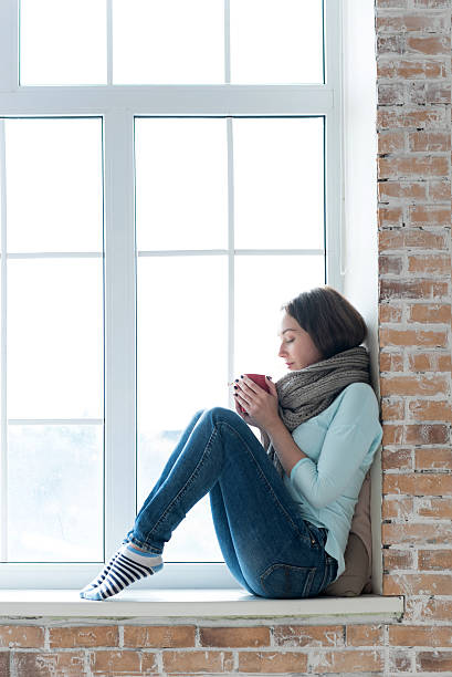 istock Attractive young woman sitting alone on a windowsill 616262046