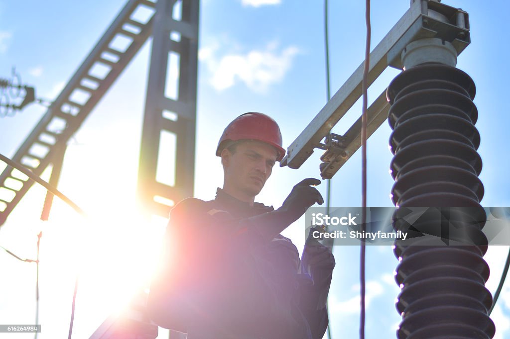 Construction Worker Working in Hight with Protective Equipment Electrician with protective workwear, hardhat and protective gloves working in power substation. Electricity Stock Photo