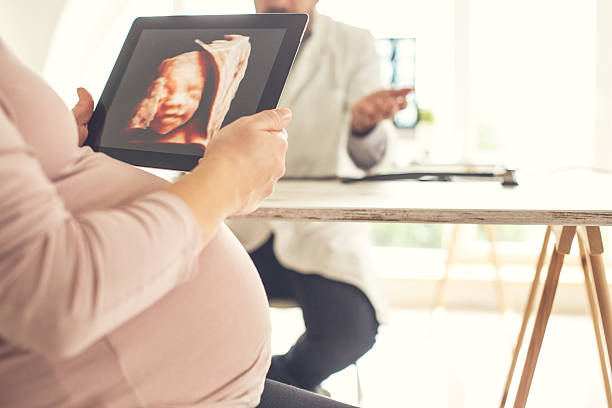 妊娠中の母親に赤ちゃんの超音波画像を示す医師 - two dimensional shape ストックフォトと画像