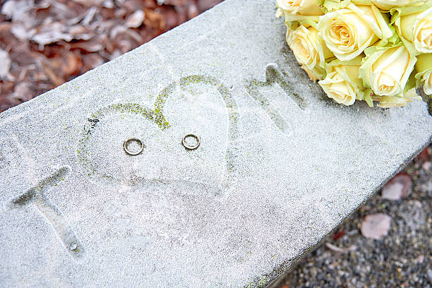 istock Initials, wedding rings and white roses on a frozen surface 616853216