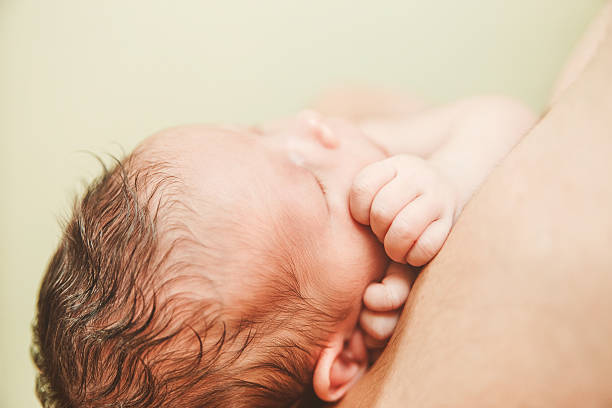 istock Part of Face Newborn Baby.Small Touching Hands. 616862132