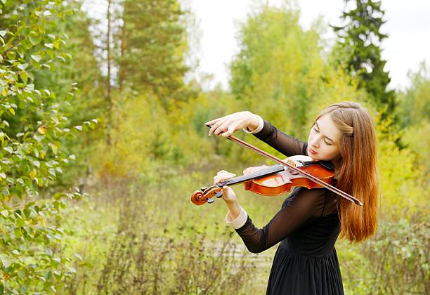 istock Girl with violin in the forest 616869146