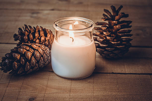 istock Burning candle and pine cones on wood background 616871000