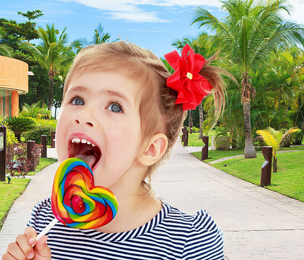 istock Girl licks candy on a stick 616872162