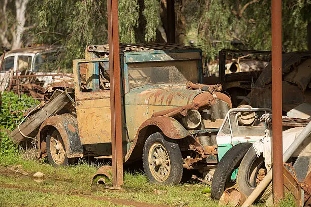 Old rusted car body and other car parts in a rural paddock