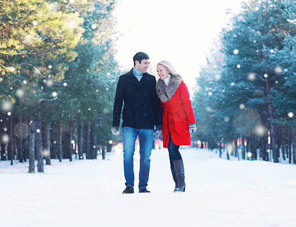 happy young smiling couple walking together in winter forest stock photo