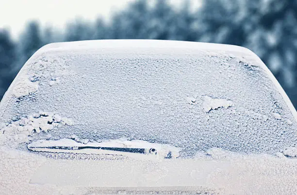 Photo of Winter frozen back car window, texture freezing ice glass background