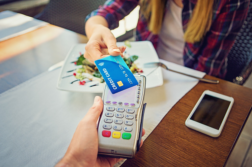 Young girl is paying for her salad using her contactless credit card 