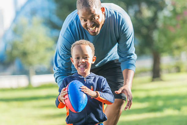 istock Little boy and father playing in the park with ball 616883230