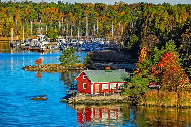 Red summer cabin or mokki in fall color forest on rocky shore of Baltic Sea. Ruissalo island, Turku archipelago, Finland