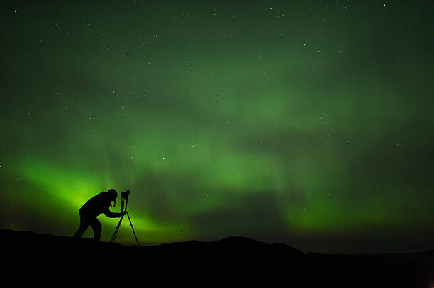 silhouette of photographer shooting aurora