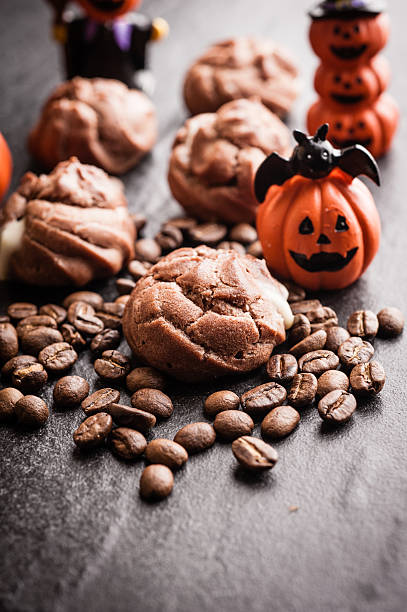 istock Eclairs and coffee beans with halloween decoration on black background 616890860