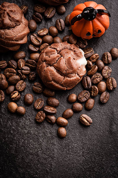 istock Eclairs and coffee beans with halloween decoration on black background 616890870