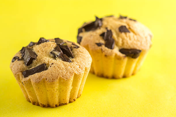 Muffins with pieces of chocolate. Yellow background. stock photo